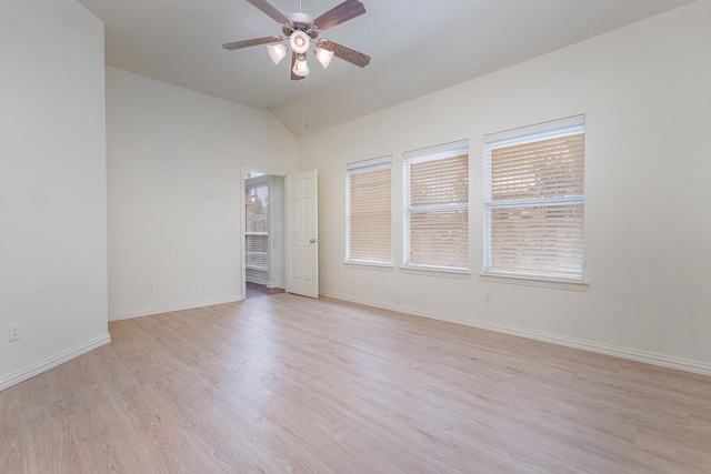 empty room featuring lofted ceiling, ceiling fan, light wood-style flooring, and baseboards