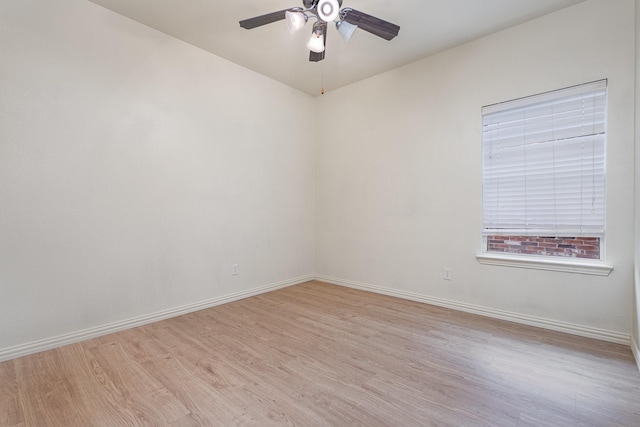 spare room with light wood-type flooring, a ceiling fan, and baseboards