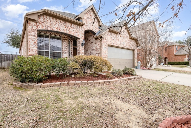 french country inspired facade featuring a garage, driveway, brick siding, and fence