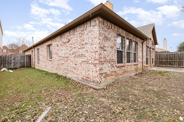 view of property exterior featuring a fenced backyard, a chimney, a lawn, and brick siding