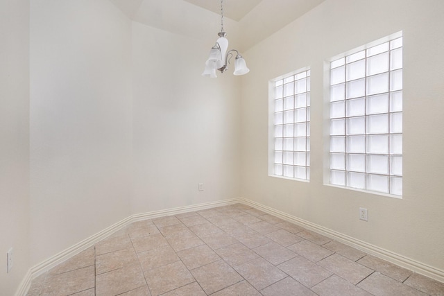 empty room with light tile patterned floors, baseboards, and an inviting chandelier