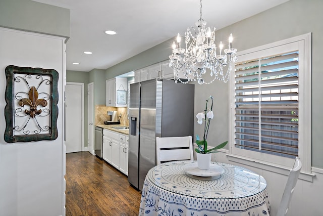 kitchen with decorative backsplash, appliances with stainless steel finishes, decorative light fixtures, light countertops, and white cabinetry