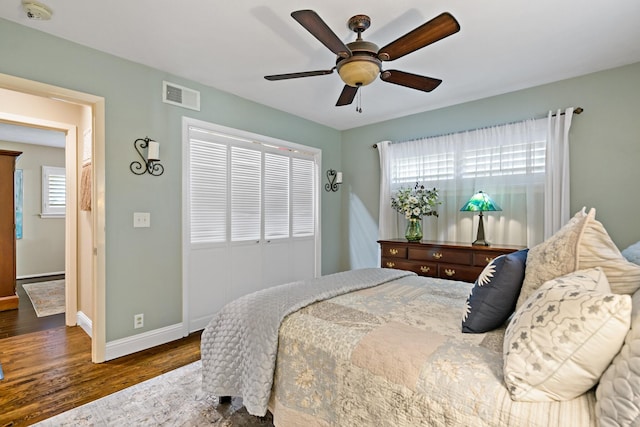 bedroom with visible vents, dark wood finished floors, baseboards, and multiple windows