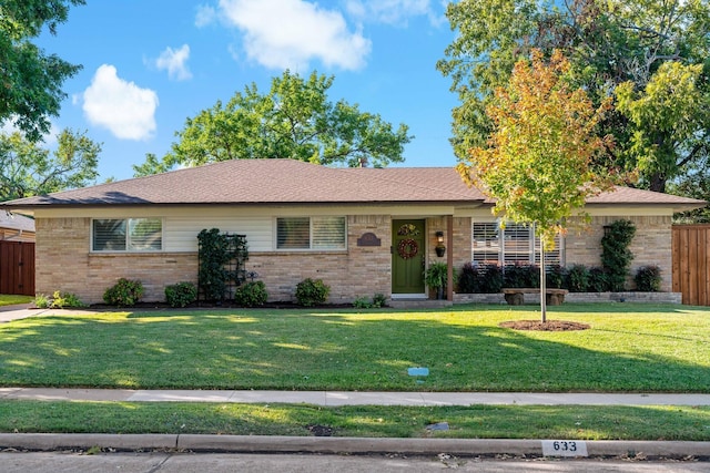 ranch-style home with brick siding, roof with shingles, a front yard, and fence