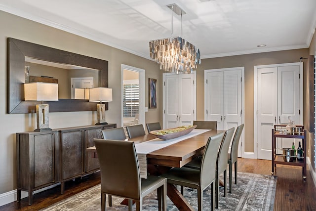 dining area featuring dark wood-type flooring, crown molding, baseboards, and an inviting chandelier