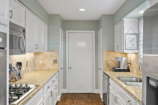 kitchen with appliances with stainless steel finishes, a sink, light stone counters, and white cabinets