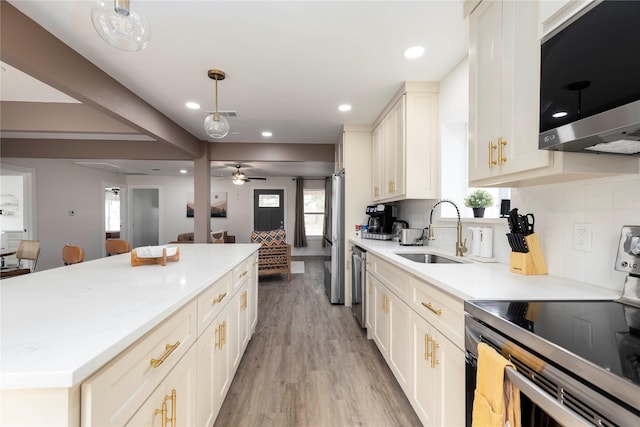 kitchen featuring pendant lighting, stainless steel appliances, backsplash, open floor plan, and a sink