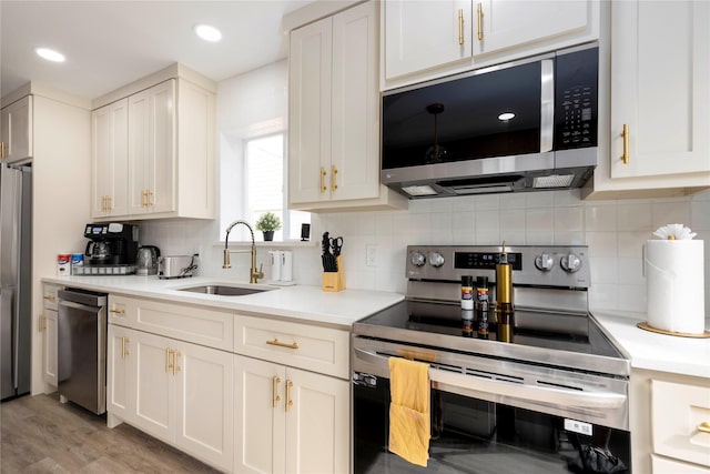 kitchen with appliances with stainless steel finishes, light countertops, a sink, and decorative backsplash