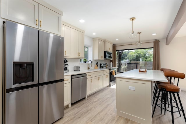 kitchen featuring stainless steel appliances, light countertops, hanging light fixtures, and a kitchen island