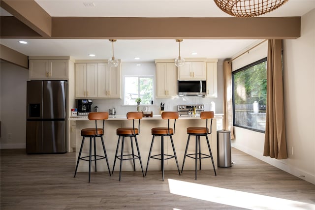 kitchen with light countertops, appliances with stainless steel finishes, a breakfast bar area, and decorative light fixtures