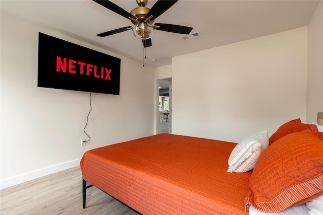 bedroom featuring ceiling fan, wood finished floors, visible vents, and baseboards