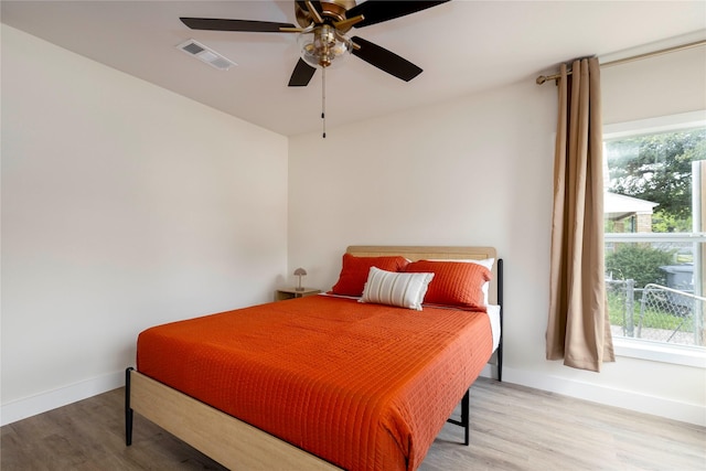 bedroom with wood finished floors, visible vents, and multiple windows