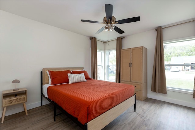 bedroom with dark wood-type flooring, a ceiling fan, and baseboards