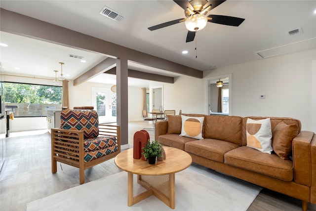 living room with light wood-style floors, beam ceiling, and visible vents