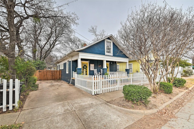 bungalow-style house with covered porch and a fenced front yard