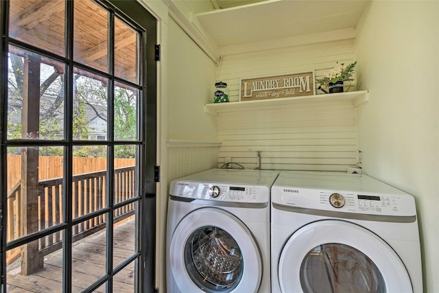 clothes washing area with laundry area, wooden walls, washer and clothes dryer, a wainscoted wall, and wood finished floors