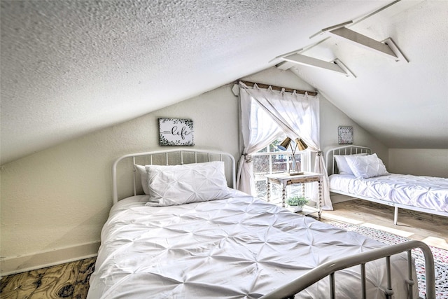 bedroom with vaulted ceiling, a textured ceiling, baseboards, and wood finished floors