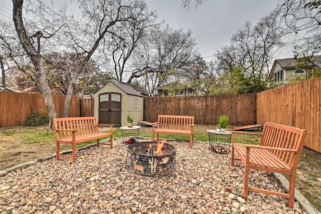 view of yard with an outdoor fire pit, a fenced backyard, an outbuilding, and a storage shed