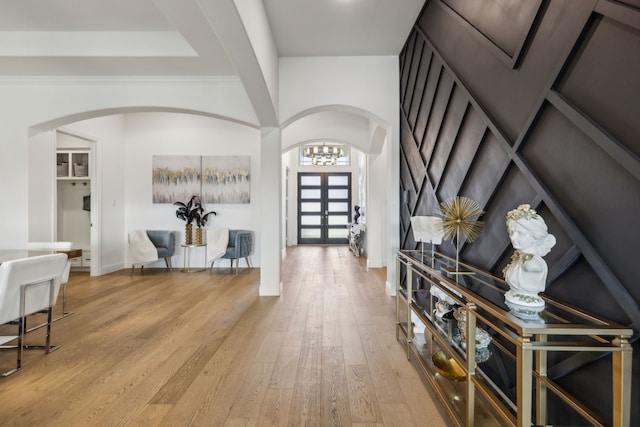 foyer with arched walkways, french doors, wood finished floors, and baseboards