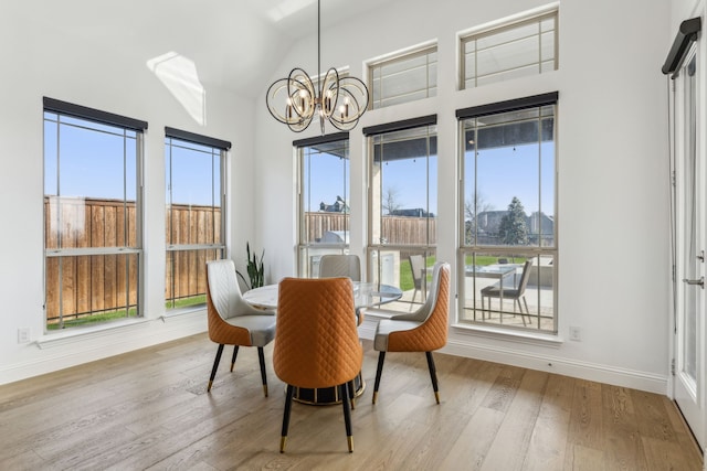 dining room featuring a chandelier, baseboards, high vaulted ceiling, and light wood finished floors