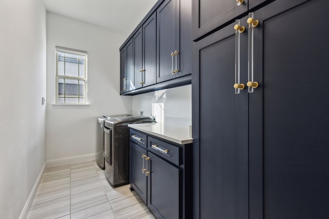 washroom featuring baseboards, cabinet space, and washer and dryer