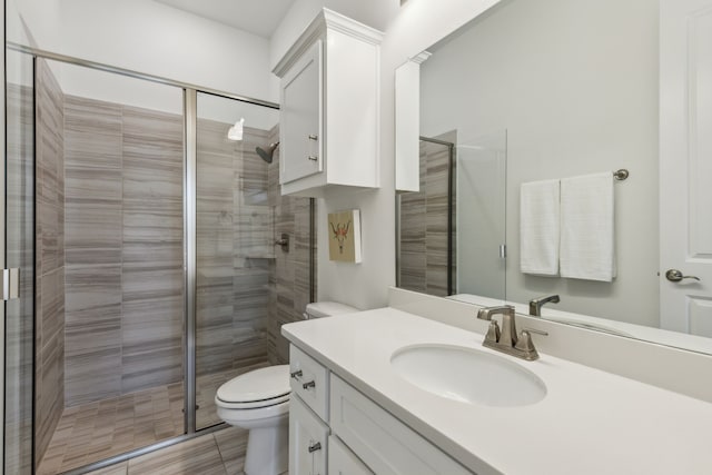 bathroom with a shower stall, toilet, and vanity