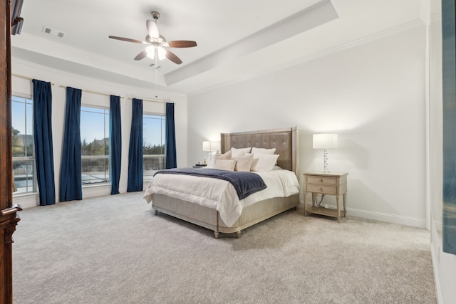 bedroom featuring light carpet, a tray ceiling, visible vents, and baseboards