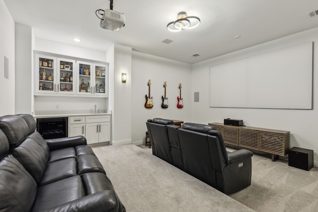 home theater featuring wine cooler, indoor wet bar, light colored carpet, a sink, and baseboards