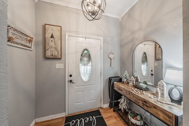 entryway featuring baseboards, an inviting chandelier, wood finished floors, and crown molding