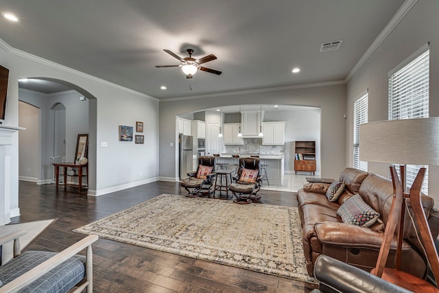 living area with baseboards, visible vents, a ceiling fan, arched walkways, and dark wood-type flooring