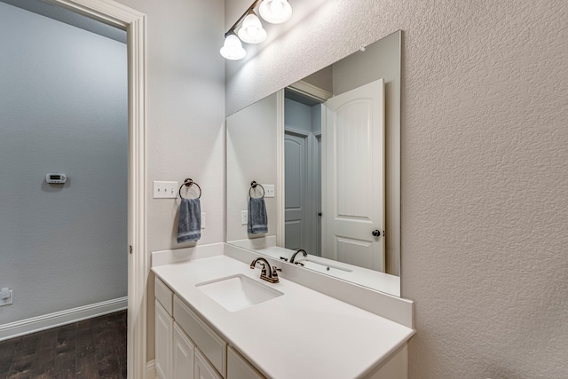 bathroom featuring a textured wall, wood finished floors, vanity, and baseboards