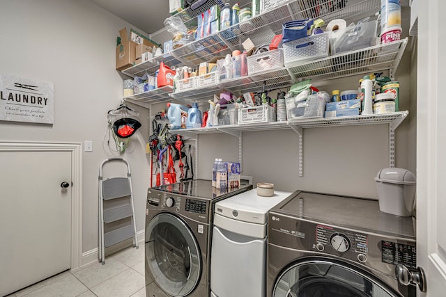 laundry area with laundry area, baseboards, washing machine and clothes dryer, and light tile patterned floors