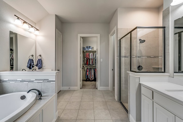 full bathroom with a walk in closet, a garden tub, a stall shower, vanity, and tile patterned flooring