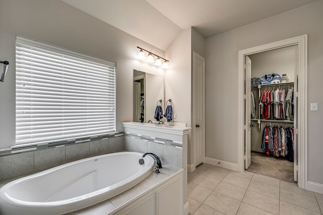 bathroom featuring a walk in closet, a garden tub, baseboards, and tile patterned floors