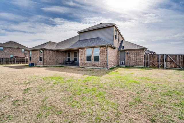 rear view of property with brick siding, fence, and a yard