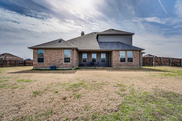 back of house with a fenced backyard, a shingled roof, and brick siding