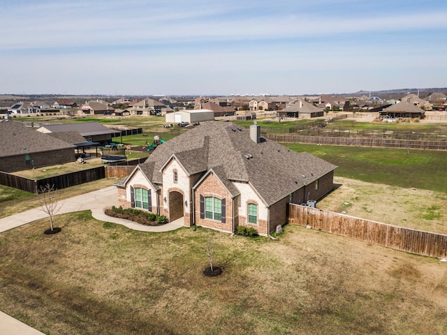 view of front of property featuring brick siding, a front lawn, a fenced backyard, and a residential view