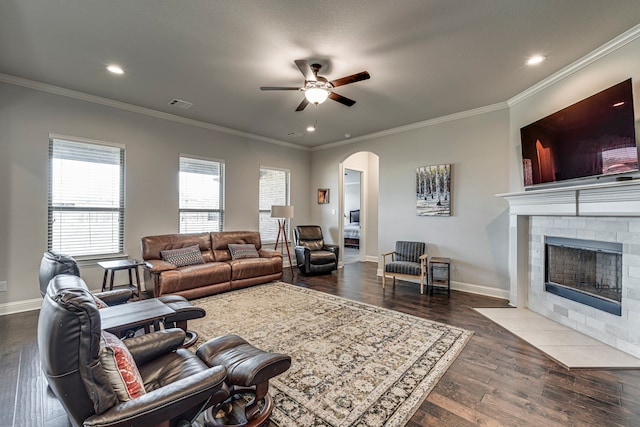 living area featuring arched walkways, visible vents, a fireplace with flush hearth, dark wood-type flooring, and baseboards