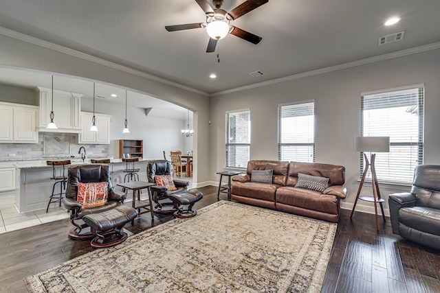 living area with ornamental molding, visible vents, and baseboards