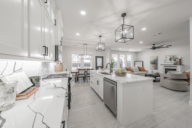 kitchen with white cabinetry, open floor plan, hanging light fixtures, appliances with stainless steel finishes, and an island with sink