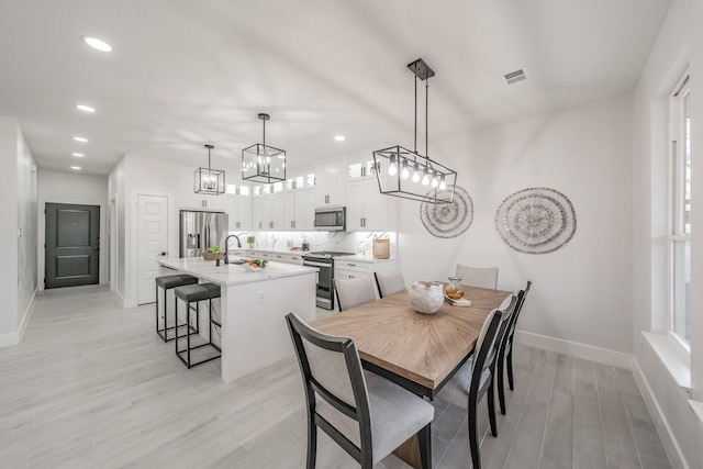 dining area with light wood finished floors, recessed lighting, visible vents, an inviting chandelier, and baseboards