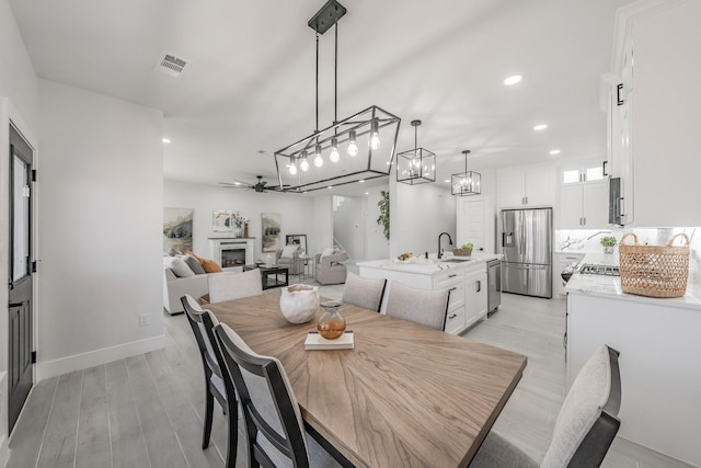 dining room featuring recessed lighting, a fireplace, visible vents, baseboards, and light wood-style floors