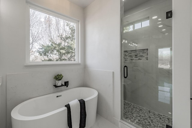 full bathroom featuring a soaking tub, a shower stall, marble finish floor, and a wealth of natural light