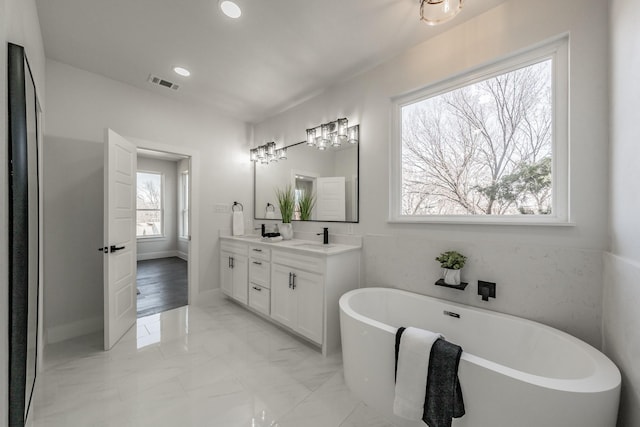 bathroom featuring a freestanding tub, a sink, visible vents, marble finish floor, and double vanity