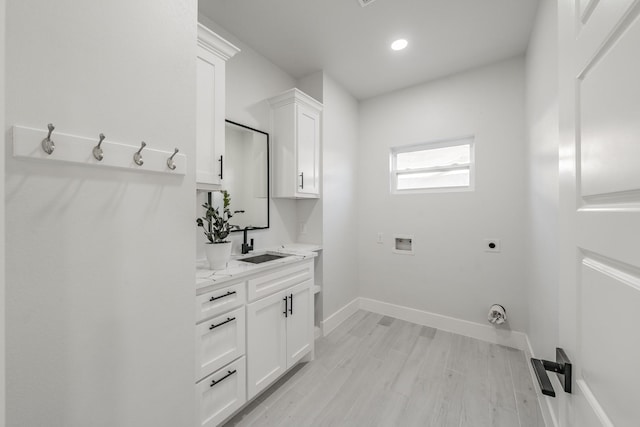 washroom with cabinet space, light wood-style flooring, hookup for an electric dryer, a sink, and baseboards