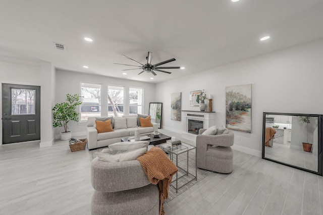 living room with recessed lighting, visible vents, a fireplace, and light wood-style flooring