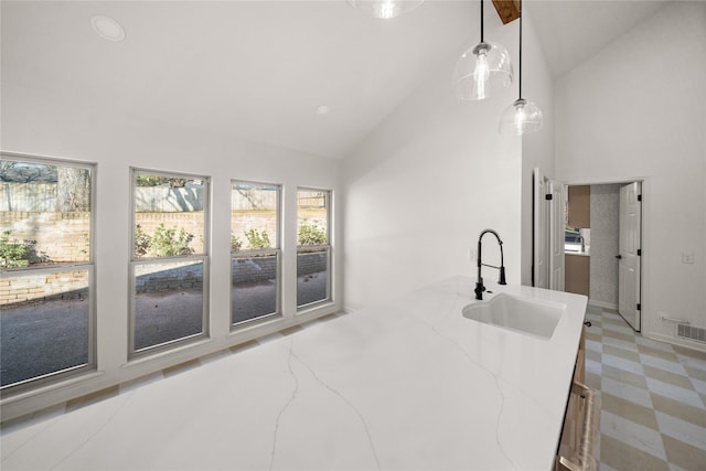 3829 Cloverdale Dr, Tyler, TX 75701 - kitchen with a sink, high vaulted ceiling, light stone countertops, light floors, and pendant lighting