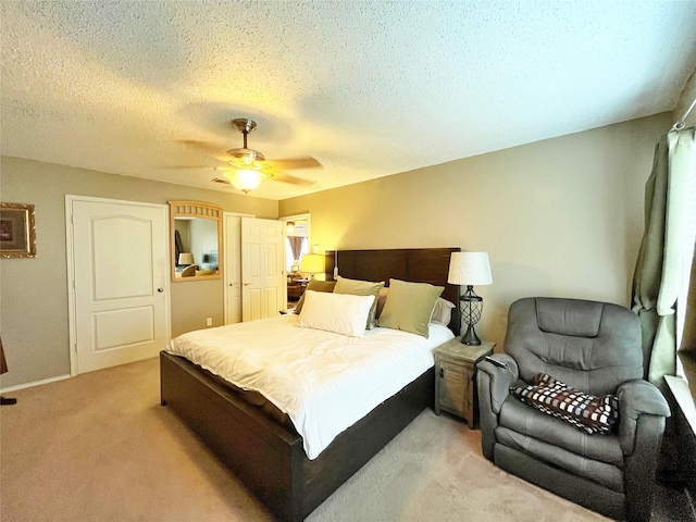 bedroom featuring a ceiling fan, light carpet, a textured ceiling, and baseboards