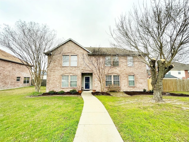 view of front of property with brick siding, a front yard, and fence