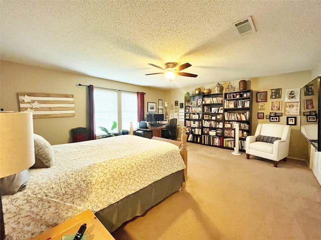 carpeted bedroom featuring ceiling fan, visible vents, and a textured ceiling